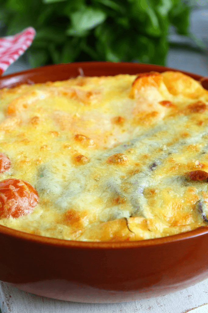 A close-up of a baked Chili Relleno Casserole with a golden-brown, bubbly cheese topping and visible roasted peppers.