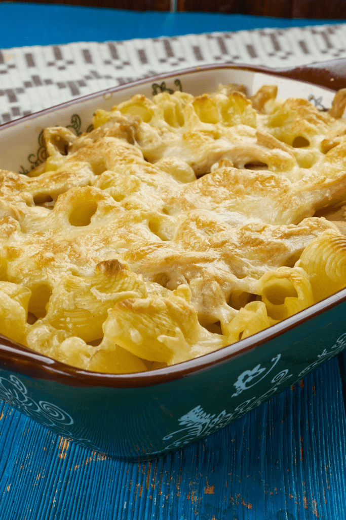 A golden brown chicken tortilla casserole in a green ceramic baking dish, topped with melted cheese and tortilla chips.