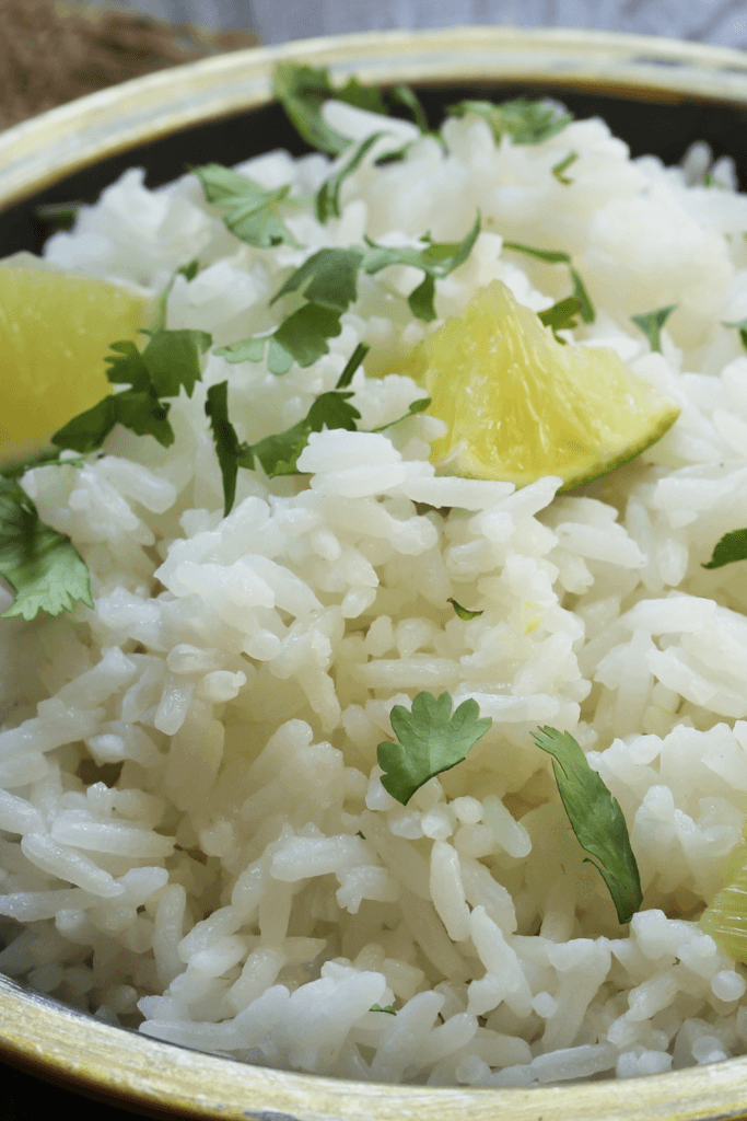 A close-up view of cilantro lime rice, garnished with fresh cilantro leaves and lime wedges.