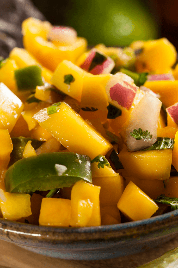 Close-up of a bowl of mango habanero salsa with diced mangoes, green peppers, red onions, and cilantro.