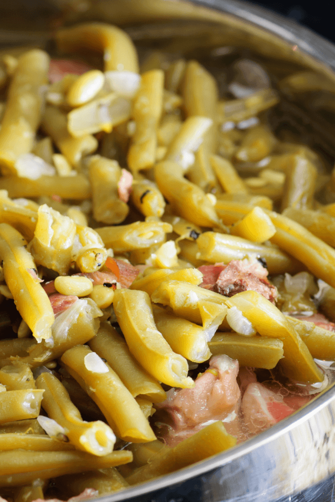 Close-up of cooked green beans mixed with pieces of bacon and onions.