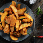 Crispy baked potato wedges with a sprinkle of fresh herbs on a white plate.